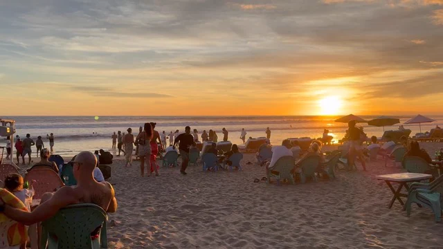 People on a beach watching the sun set over the sea