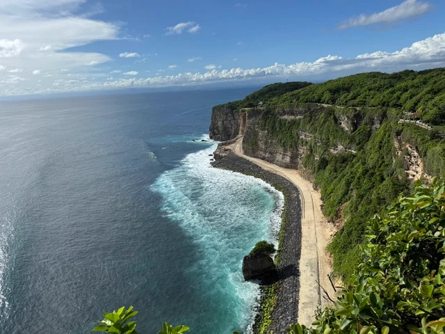 A long sandy beach beneath steep coastal cliffs in Bali