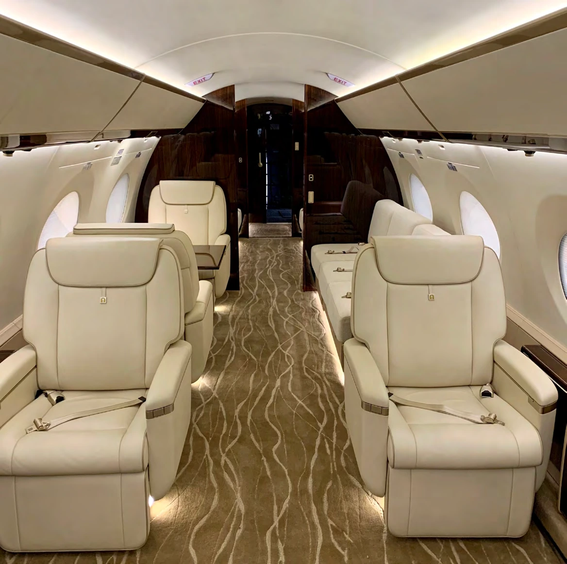 Forward cabin with four cream leather club seats and a view toward the rear cabin
