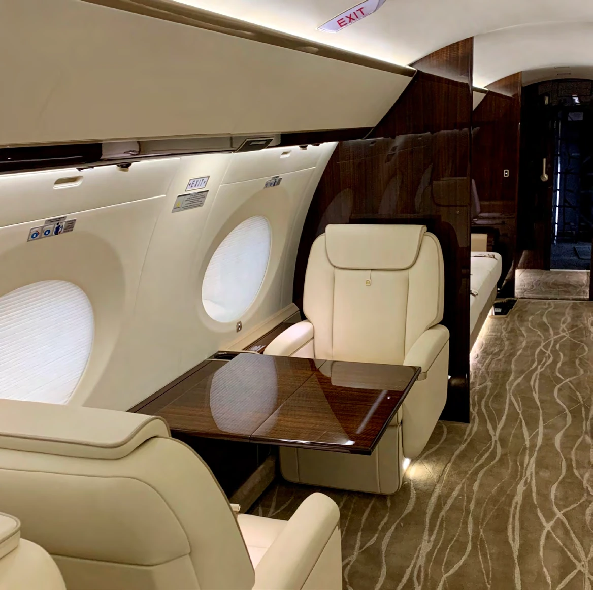 Two cream leather club seats with a polished wood table