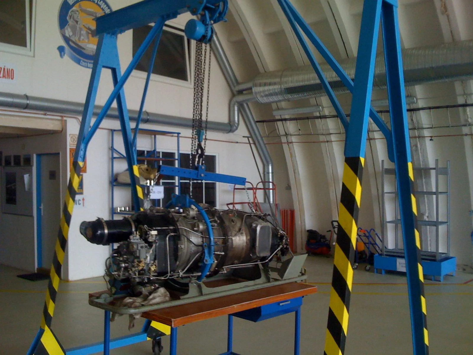 A wider view of the engine and blue lifting frame in the workshop