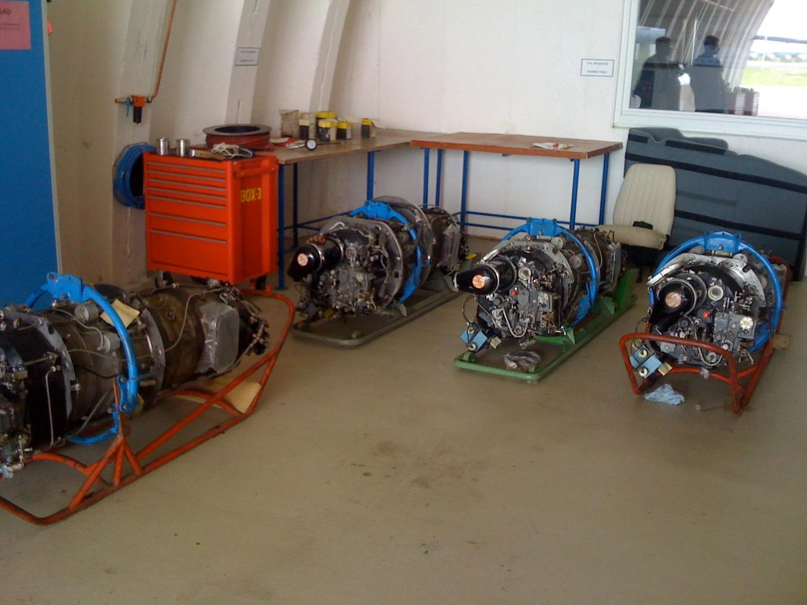 Several engines on transport frames beside a workshop bench